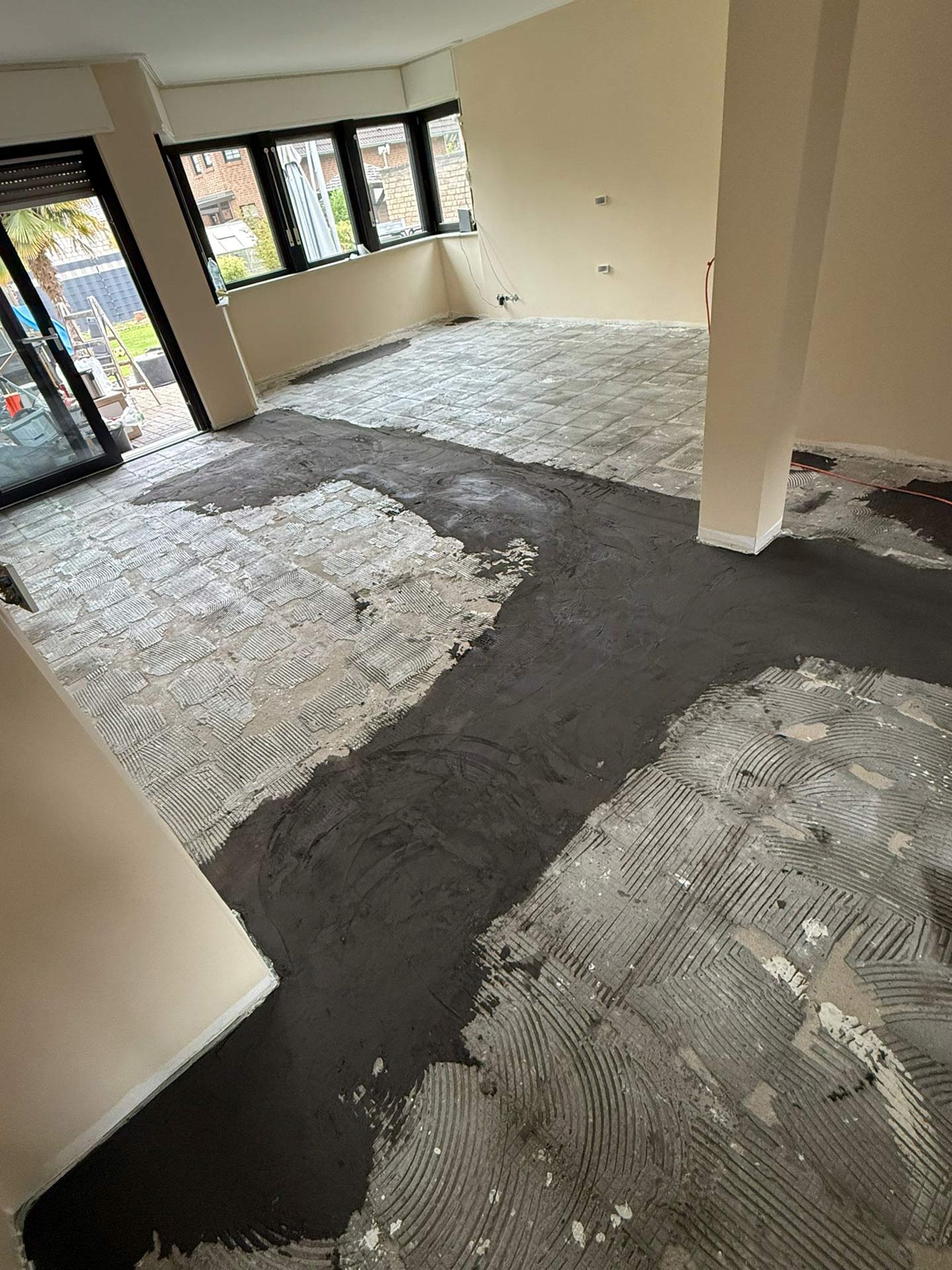 Leerer Raum mit grauem Estrich und schwarzer Spachtelmasse, große Fenster
