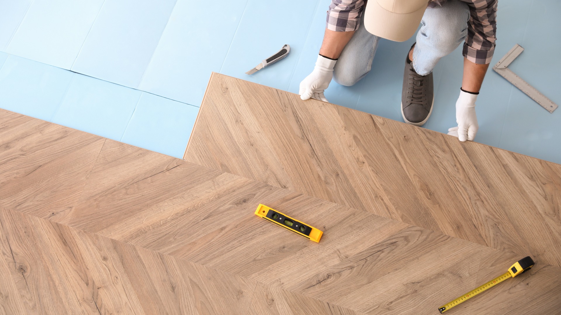 Arbeiter beim Verlegen eines Laminatbodens in Innenräumen, Ansicht von oben