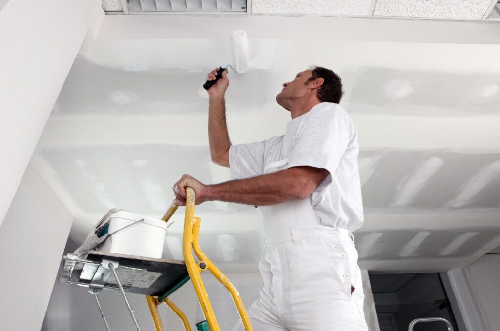 Ein Handwerker, der eine Decke streicht
